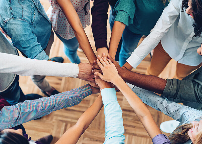 Men and Women of all races putting their hands in a circle on top of each other